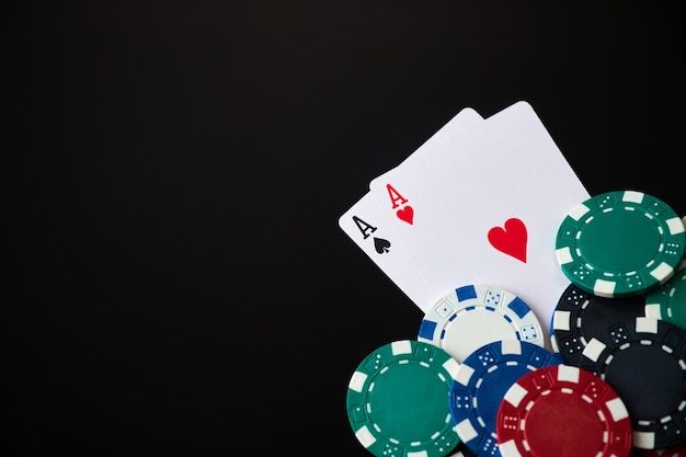 Casino chips and playing cards on dark reflective background