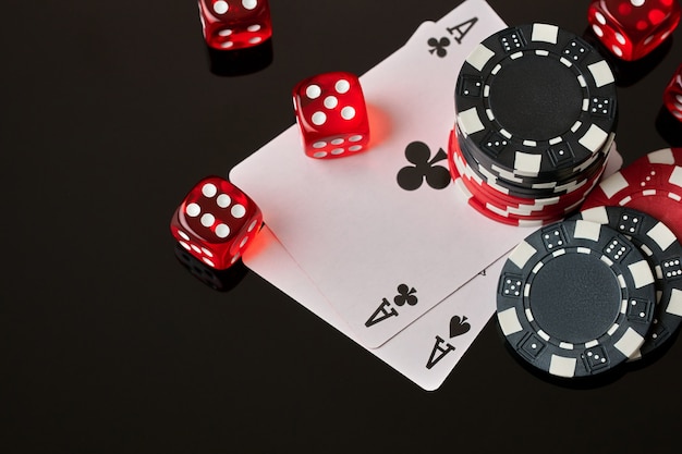 Casino chips playing cards and dices on dark reflective background