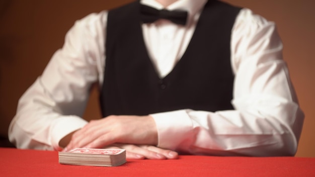 Casino dealer shuffles cards on red table hands close up