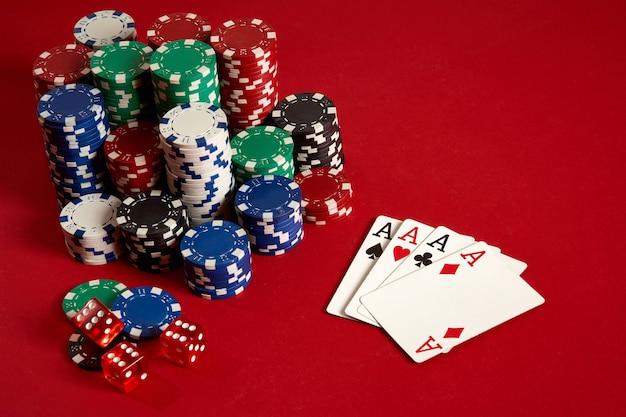 Casino gambling poker equipment and entertainment concept - close up of playing cards and chips at red background. Four of a Kind. Casino background. Copy space. Still life