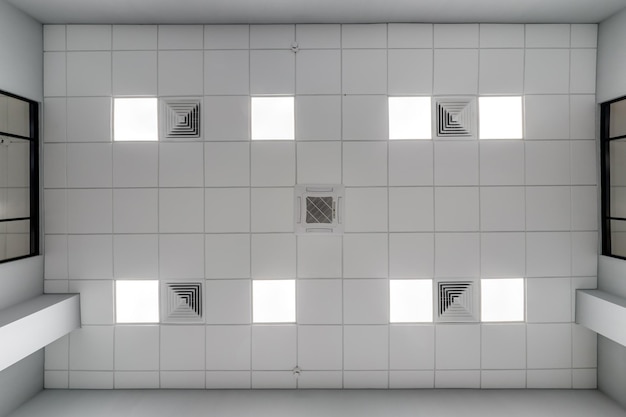 Cassette suspended ceiling with square halogen spots lamps and drywall construction in empty room in apartment or house Stretch ceiling white and complex shape Looking up view