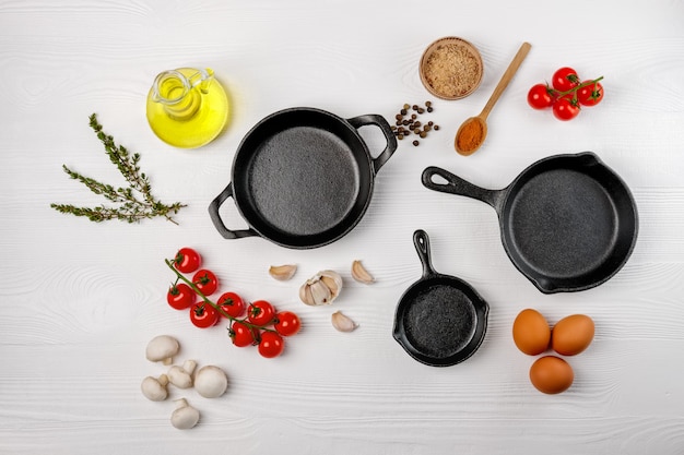 Cast iron skillets and spices on white wood