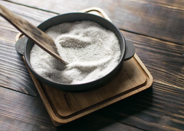 Castiron fry pan with salt on a wooden background Prepare the frying pan for first use