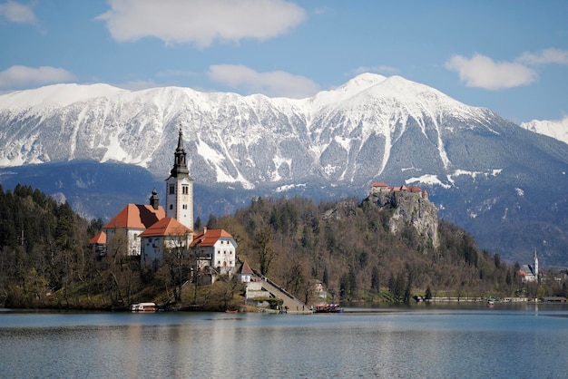 A castle on a hill with snow on the mountains behind it