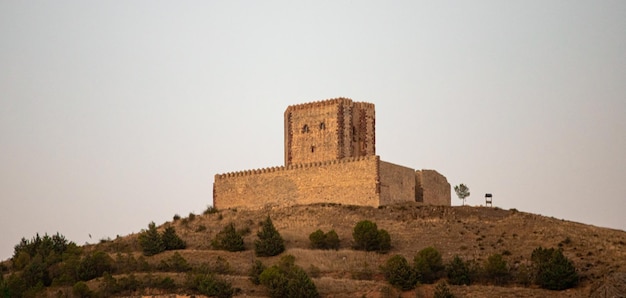 A castle on a hill with the sun setting behind it