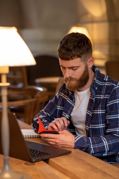 Casual business man or freelancer planning his work on notebook, working on laptop computer with smart phone, cup of coffee on table at coffee shop or home office, working from cafe concept