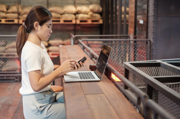 Casual Businesswoman using smartphone and laptop freelance woman typing keyboard computer notebook in cafe or modern office technology digital online and network concept