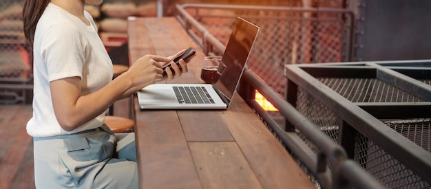 Casual Businesswoman using smartphone and laptop freelance woman typing keyboard computer notebook in cafe or modern office technology digital online and network concept