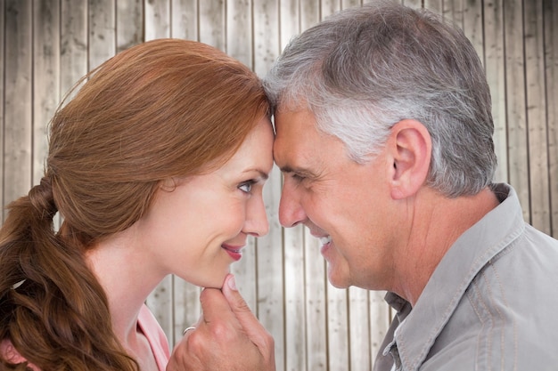 Casual couple smiling at each other against wooden planks background