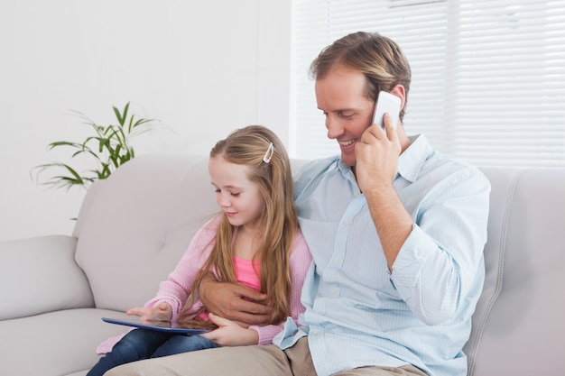 Casual father and daughter using tablet on the couch