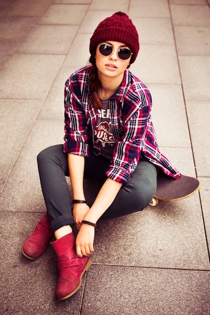 Casual, hipster styled woman sitting on the floor in sunglassess