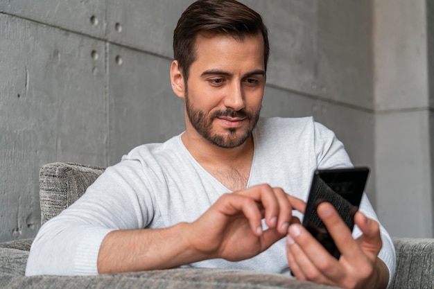 Casual man using smartphone in armchair