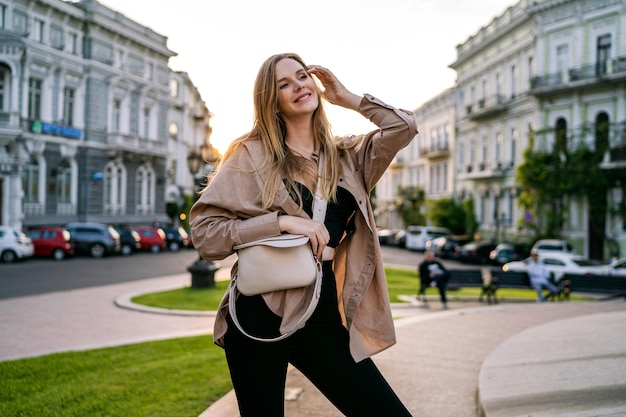 Casual oudoor city postrait of stylish blonde woman walking alone having fun on sunset time