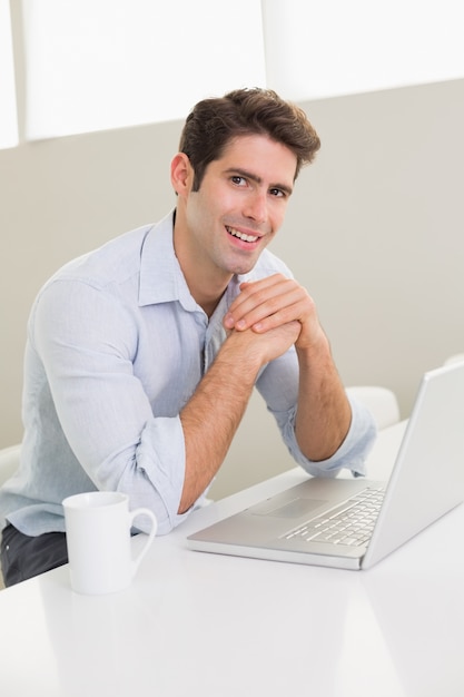 Casual smiling man using laptop at home