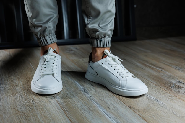 Casual white sneakers for men Male legs in white leather summer shoes Comfortable men's white sneakers with laces