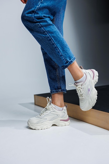 Casual women's fashion Sports shoes for women Slender female legs in jeans and white stylish casual sneakers Women's comfortable summer shoes