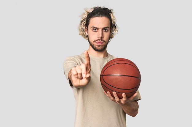 Casual young basketball player in studio showing number one with finger