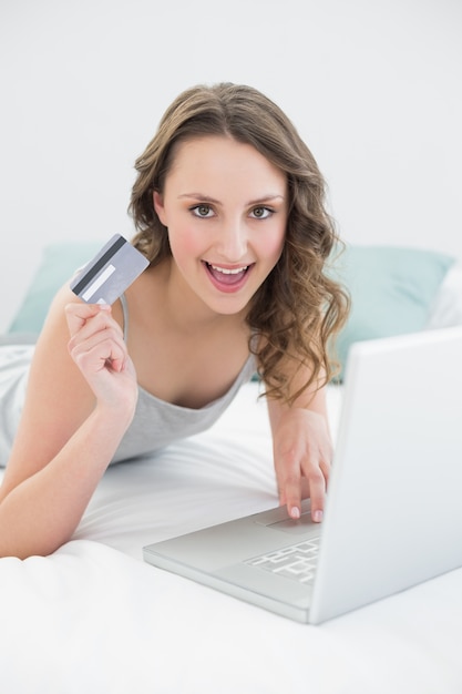 Casual young woman doing online shopping in bed