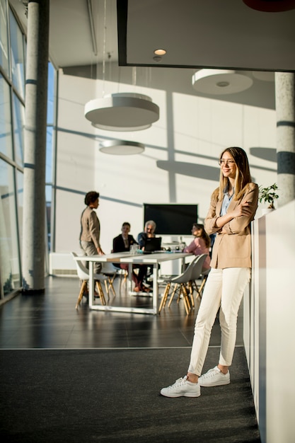 Casual young woman standing in a busy modern workplace