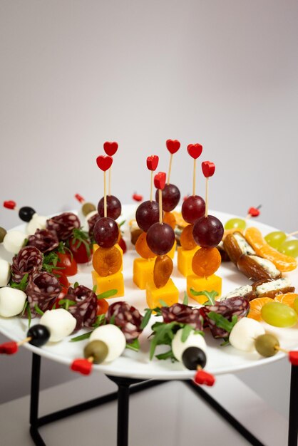 Photo catering snacks with sausage cheese and fruit on a stand