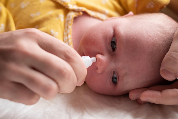 Photo caucasian aby gets nose drops mom puts drops in the nose of the child