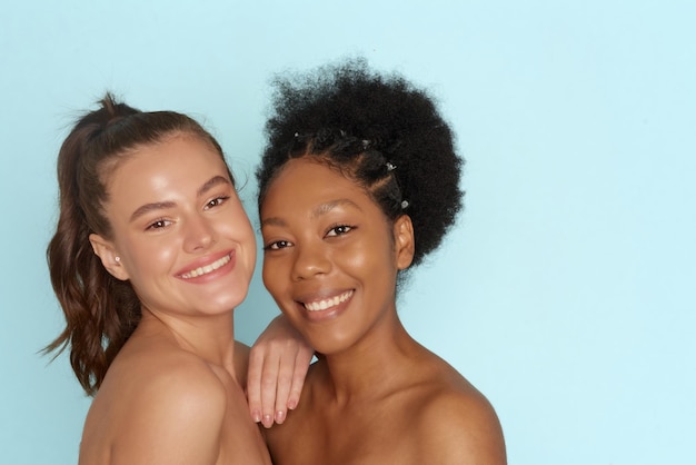 Caucasian and african american women with perfect skin on blue background with copy space Skin care