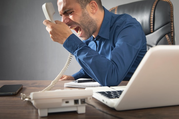 Caucasian angry businessman screams into the telephone receiver