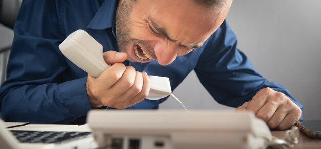 Caucasian angry businessman screams into the telephone receiver