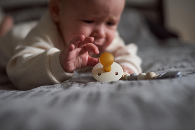 Caucasian baby boywith with pacifier on bed in the parents bedroom Pretty sixmonth old baby boy Realistic toddler home portrait