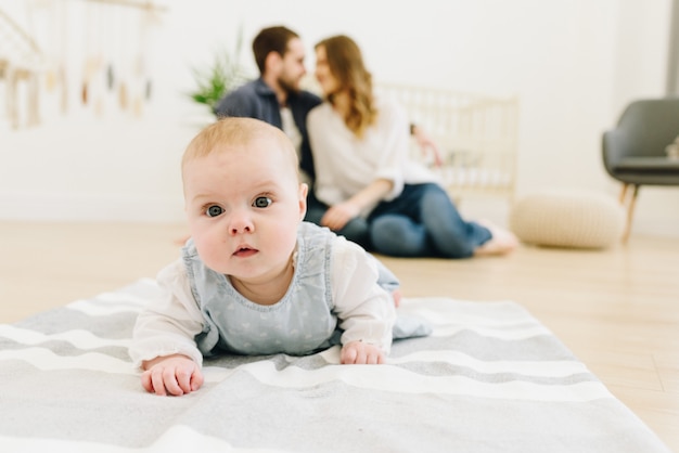 Caucasian baby crawling on the floor of nursery with her parents