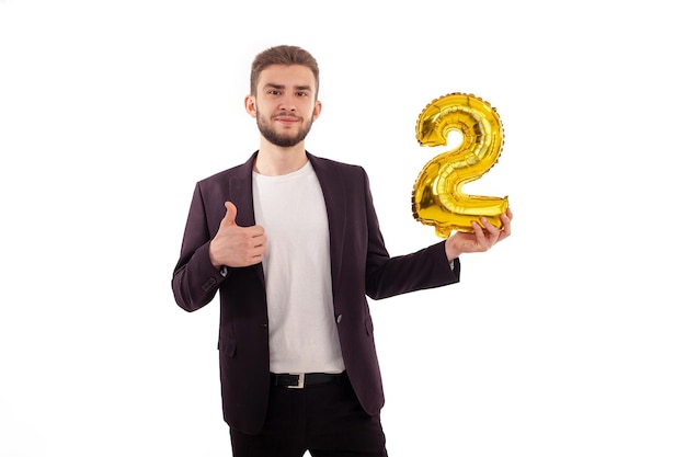 Caucasian bearded man holding a yellow inflatable number two wearing a classic suit