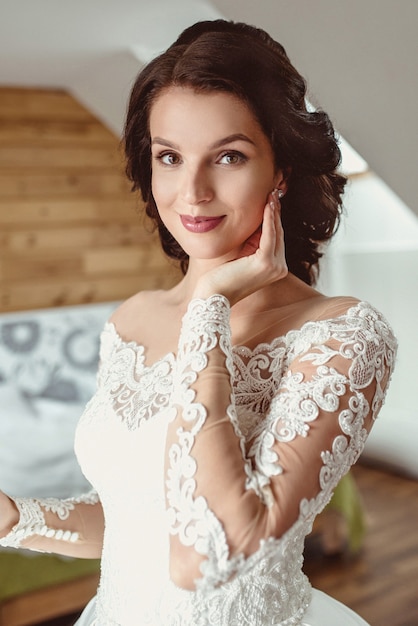 caucasian beautiful woman bride in traditional european white dress standing by the window