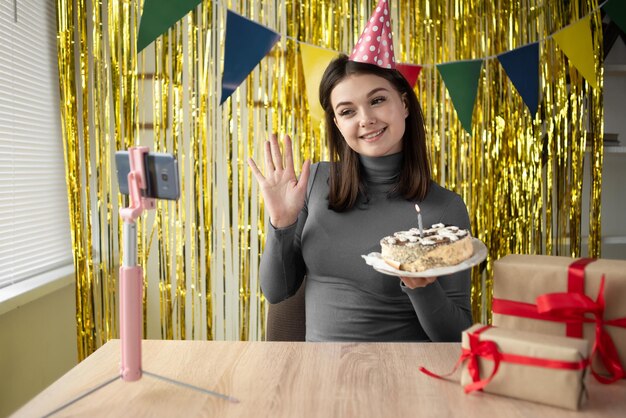 A Caucasian blogger blogging about a birthday at home holds a cake in his hands and sits at a table with a phone on a tripod A brunette girl at home shows a homemade festive dessert