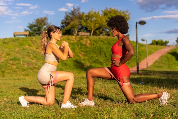 Caucasian blonde girl and dark-skinned girl with afro hair doing stretching