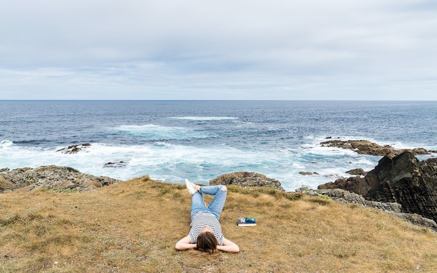 Caucasian blonde woman lying on the grass relaxing by the sea