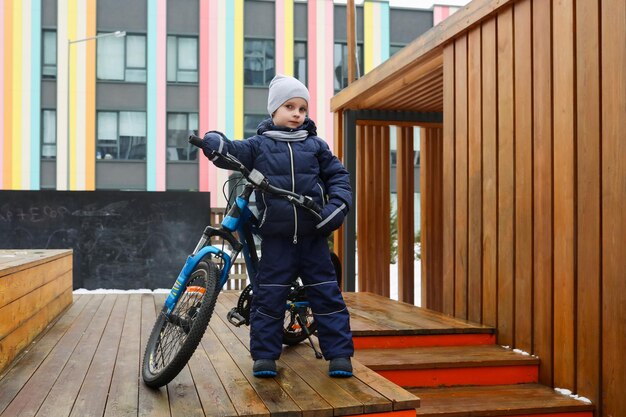 A caucasian boy asked to take his bike for a walk in winter