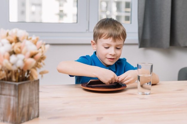 Caucasian boy breaks a large bar of chocolate to eat it