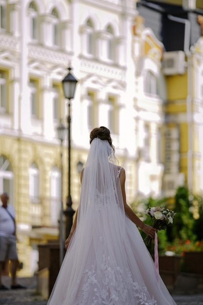 caucasian bride in a white dress walks along the ancient streets during a wedding photo shoot