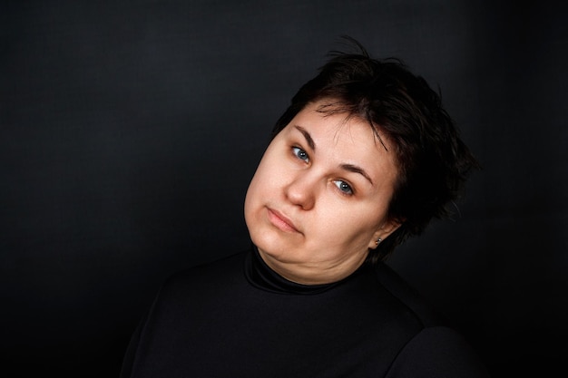 Caucasian brunette woman with a sad look on a black background High quality photo