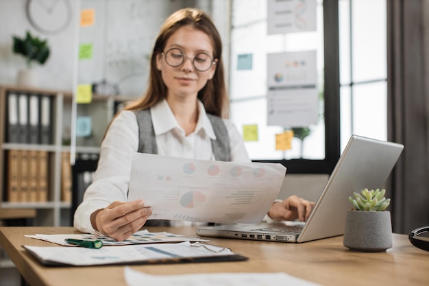 Caucasian business woman in eyeglasses using laptop for video conference at office