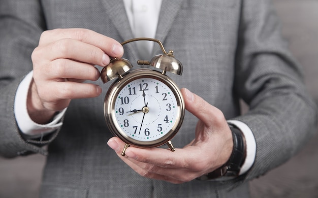 Caucasian businessman holding alarm clock.