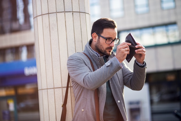 Caucasian businessman looking at empty wallet