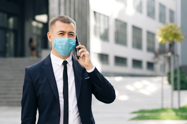 Caucasian businessman in medical mask talking on phone