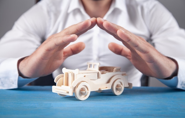 Caucasian businessman protect wooden toy car.