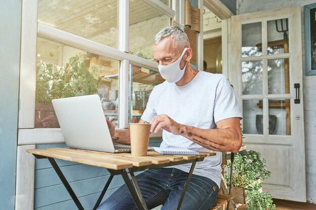 Caucasian businessman in protective mask working on laptop