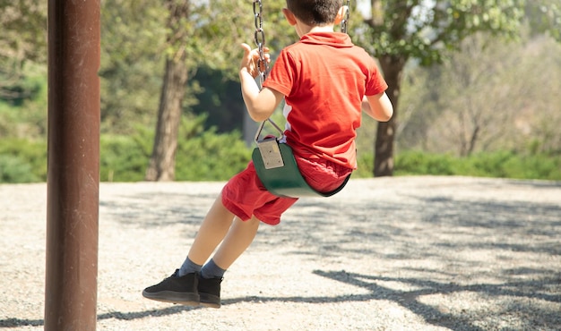 Caucasian child boy is swinging on a swing