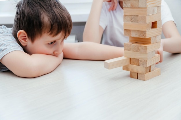 Caucasian children boy and girl playing jenga Block stacking game Home family activity party board offline game concept while staying at home during quarantine