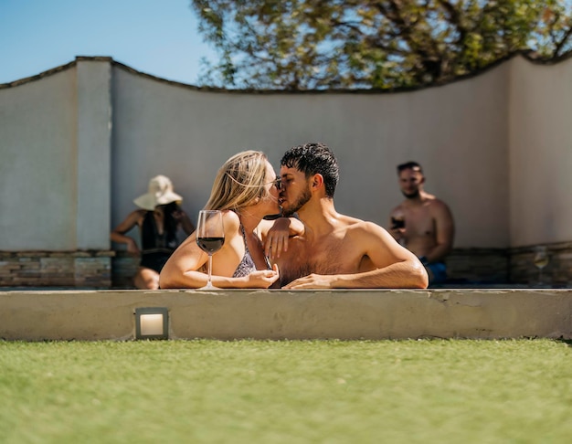 Caucasian couple kissing leaning on the edge of a swimming pool