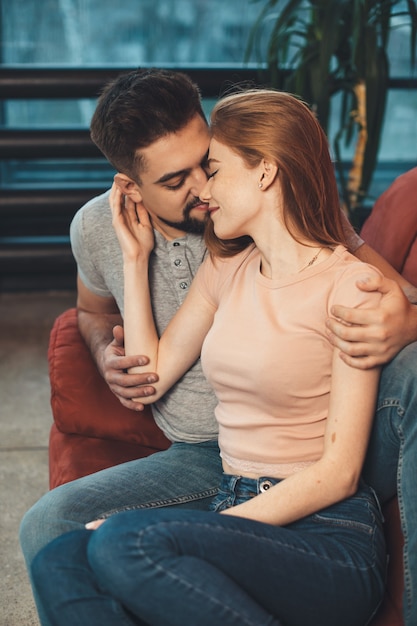 Caucasian couple sitting on a red couch embracing and celebrating a date together