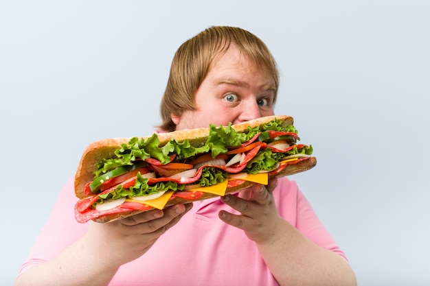 Caucasian crazy blond fat man holding a giant sandwich